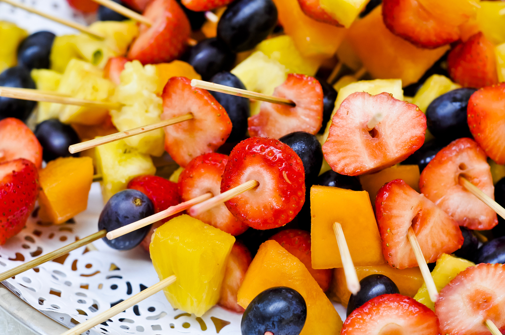 Fruit on sticks on a tray.