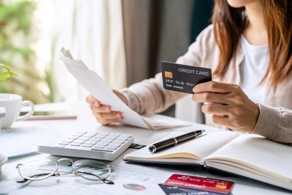 Woman looking at her credit card and papers while studying healthy financial habits.